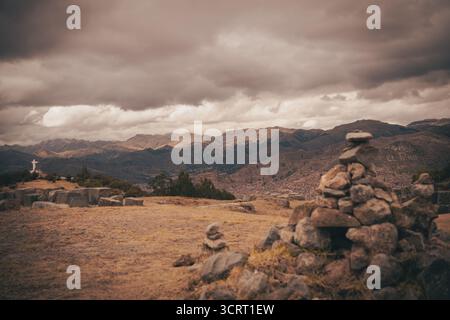 Blick auf Cusco und die umliegenden Anden vom Aussichtspunkt Cristo Blanco in der Nähe von Sacsayhuamán, mit steinhügeln im Vordergrund. Stockfoto
