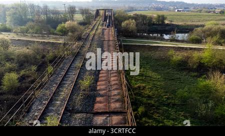 Luftaufnahme einer stillgelegten Eisenbahnbrücke mit stillgelegten Gleisen und Rostbau Stockfoto