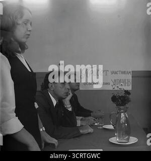 Ein authentisches Schwarz-weiß-Archivfoto aus den 1970er Jahren zeigt eine Gedenkveranstaltung in Sloviansk, Ukrainische SSR. Ein sowjetischer Veteran des Großen Vaterländischen Krieges (2. Weltkrieg) mit einer Medaille auf seinem Anzug sitzt nachdenklich an einem Tisch des Präsidiums. Hinter ihm steht ein Banner an der Wand auf Russisch: "Grüße an die Teilnehmer der Befreiung der Ukraine". Dieses ergreifende Bild fängt einen feierlichen Moment der Erinnerung ein, eine typische patriotische Zeremonie zu Ehren der Kriegshelden in der UdSSR während der Breschnew-Ära Stockfoto