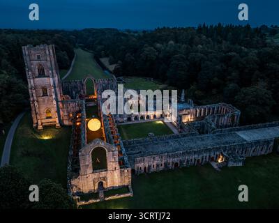 Helios, eine sieben Meter hohe Sonnenskulptur und Soundlandschaft von Luke Jerram, hängt im Schiff der beleuchteten Abteiruinen der Fountains Abbey in der Nähe von Aldfield, Ripon in North Yorkshire. Bilddatum: Donnerstag, 2. Oktober 2025. Stockfoto