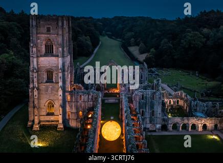 Helios, eine sieben Meter hohe Sonnenskulptur und Soundlandschaft von Luke Jerram, hängt im Schiff der beleuchteten Abteiruinen der Fountains Abbey in der Nähe von Aldfield, Ripon in North Yorkshire. Bilddatum: Donnerstag, 2. Oktober 2025. Stockfoto