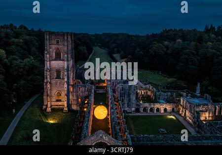 Helios, eine sieben Meter hohe Sonnenskulptur und Soundlandschaft von Luke Jerram, hängt im Schiff der beleuchteten Abteiruinen der Fountains Abbey in der Nähe von Aldfield, Ripon in North Yorkshire. Bilddatum: Donnerstag, 2. Oktober 2025. Stockfoto