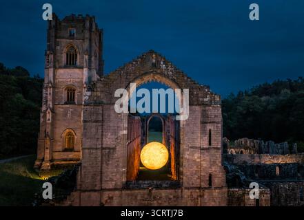 Helios, eine sieben Meter hohe Sonnenskulptur und Soundlandschaft von Luke Jerram, hängt im Schiff der beleuchteten Abteiruinen der Fountains Abbey in der Nähe von Aldfield, Ripon in North Yorkshire. Bilddatum: Donnerstag, 2. Oktober 2025. Stockfoto