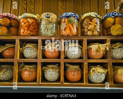 Rustikales Holzregal mit Glasgläsern mit eingelegtem Gemüse, Hülsenfrüchten und Körnern, in traditionellem Stil gelagert. Hausgemachte Bio-Produkte. Stockfoto