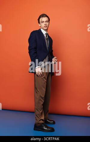 Ein junger, gutaussehender Mann steht selbstbewusst in stilvoller Kleidung und verkörpert die zeitgenössische Jugendkultur. Stockfoto