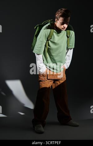 Ein trendiger Teenager steht selbstbewusst in einem stilvollen Outfit und verkörpert die zeitgenössische Jugendkultur. Stockfoto