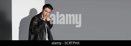 Ein junger, gutaussehender Mann steht selbstbewusst und strahlt Stil in einer trendigen urbanen Umgebung aus. Stockfoto