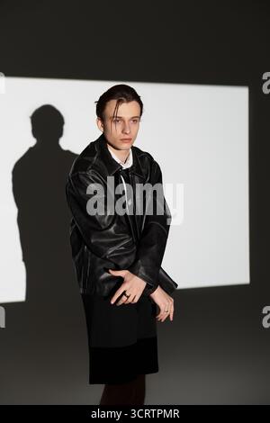 Ein modischer Teenager steht selbstbewusst in einem urbanen Umfeld, das moderne Jugendkultur ausstrahlt. Stockfoto