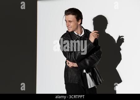 Ein trendiger Teenager steht selbstbewusst und zeigt seinen einzigartigen Stil in einer urbanen Umgebung. Stockfoto