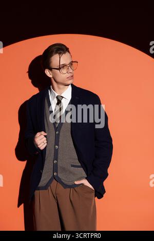 Ein hübscher Teenager steht selbstbewusst in modischer Kleidung mit auffälligen Farben im Hintergrund. Stockfoto