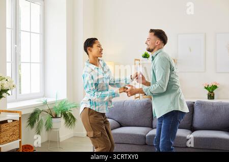 Porträt eines glücklichen, lächelnden jungen Paares, das zu Hause Spaß macht und tanzt. Stockfoto