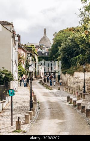 Paris, Frankreich - 11. Oktober 2025: Malerische Rue de l’Abreuvoir in Montmartre mit Blick auf die Basilika Sacre-Coeur Stockfoto