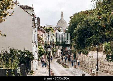 Paris, Frankreich - 11. Oktober 2025: Malerische Rue de l’Abreuvoir in Montmartre mit Blick auf die Basilika Sacre-Coeur Stockfoto