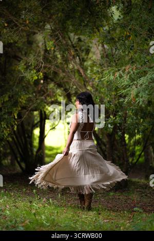 Eine junge Frau in Boho-schicker Kleidung, die im Wald tanzt Stockfoto
