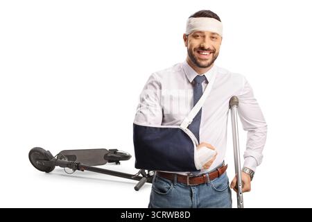 Junger Mann mit gebrochenem Arm und Bandage am Kopf erholt sich nach einem Elektrorollerunfall isoliert auf weißem Hintergrund Stockfoto