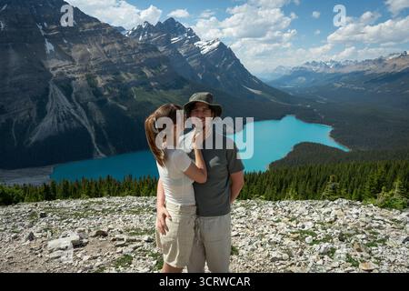 Ein Paar, das sich in den Bergen umgibt mit einem türkisfarbenen See im Hintergrund. Stockfoto