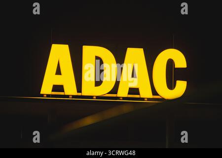 ADAC Europas größtes Markenzeichen des Automobilverbandes, das nachts im Bürogebäude leuchtet Stockfoto