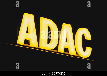 ADAC Europas größtes Markenzeichen des Automobilverbandes, das nachts im Bürogebäude leuchtet Stockfoto