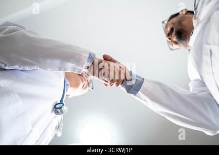 Nahaufnahme von zwei Ärzten, die die Hände schütteln, Konzept der Zusammenarbeit im Gesundheitswesen, Vertrauen und medizinische Zusammenarbeit. Stockfoto