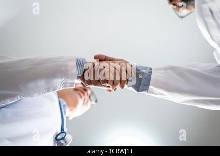 Nahaufnahme von zwei Ärzten, die die Hände schütteln, Konzept der Zusammenarbeit im Gesundheitswesen, Vertrauen und medizinische Zusammenarbeit. Stockfoto