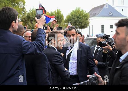 03. Oktober 2025, Saarland, Saarbrücken: Der französische Präsident Emmanuel Macron (M) wird von Journalisten umgeben und von der Öffentlichkeit begrüßt, als er während der zentralen Feierlichkeiten zum Tag der Deutschen Einheit vor der Saarländischen Landeskanzlei ankommt. Am 3. Oktober 2025 feiert Deutschland den 35. Jahrestag der deutschen Wiedervereinigung. Foto: Jean-Christophe Verhaegen/POOL AFP/dpa Stockfoto