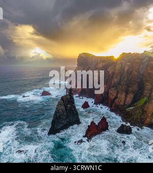 Aus der Vogelperspektive treffen zerklüftete Klippen auf das stürmische Meer unter einem dramatischen Himmel, das Zusammenspiel von Licht und Schatten schafft eine faszinierende Küstenszene, CAN Stockfoto