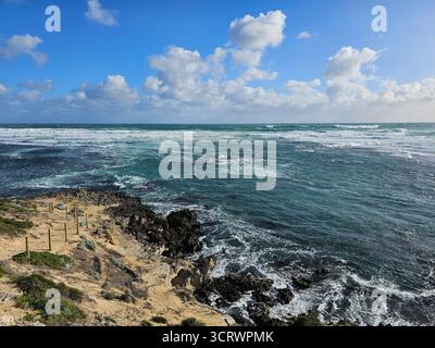 Ein malerischer Blick auf eine Küste mit Wellen, die gegen die Küste krachen. Es ist eine natürliche Landschaft mit einer felsigen Küste in WA. Stockfoto