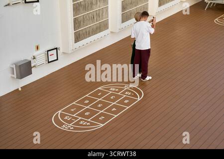 Viladecans. Spanien - 03. Oktober 2025: Ein Touristenpaar macht ein Foto mit einem Smartphone auf einem Kreuzfahrtschiff, das neben einem angestrichenen Punktspiel steht Stockfoto