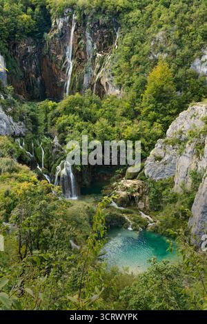Eine atemberaubende Kaskade von Wasserfällen stürzt durch üppiges Grün und zerklüftete Klippen und bildet darunter türkisfarbene Pools. Stockfoto