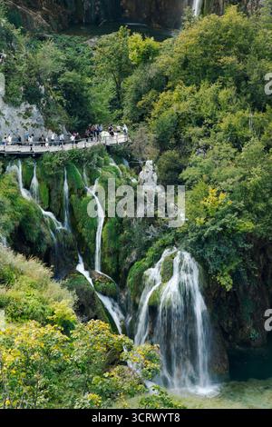 Eine atemberaubende Kaskade von Wasserfällen stürzt durch üppiges Grün und zerklüftete Klippen und bildet darunter türkisfarbene Pools. Stockfoto