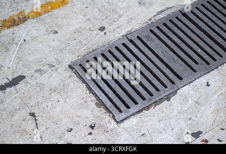 Nahaufnahme der Bodenabflussabdeckung. Der Abfluss und der umgebende Beton. Geeignet für Themen im Zusammenhang mit Bauwesen, Infrastruktur oder städtischem Bereich Stockfoto