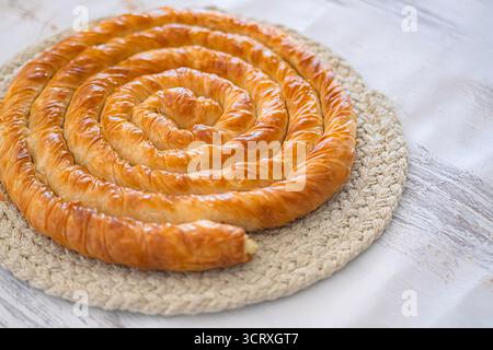 Traditioneller Spiralborek auf gewebtem Tischset frisch gebackener Spiralborek. Herzhaftes Gebäck mit blättrigem Phyllo-Teig. Selektiver Fokus. Stockfoto