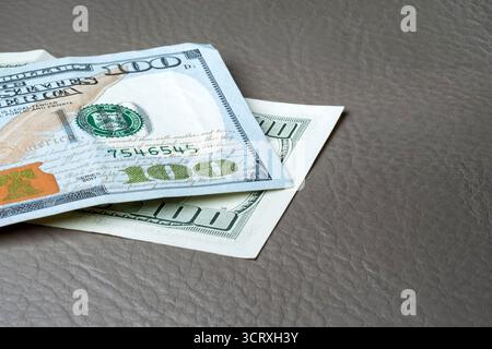 US-Dollar-Scheine auf Lederoberfläche. Nahaufnahme zweier 100-Dollar-Banknoten, die übereinander gestapelt sind. Geeignet für das Finanzbanking. Stockfoto
