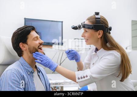 HNO-Arzt bei der oralen Untersuchung in der Klinik. Spezialist mit medizinischen Instrumenten zur Untersuchung der Kehle männlicher Patienten für Diagnose und Pflege. Stockfoto