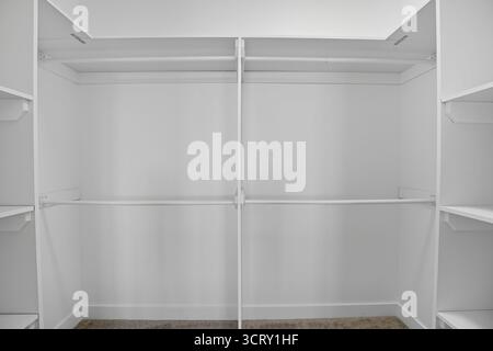 Der leere begehbare Kleiderschrank ist sehr geräumig und sauber. Die weißen Wände und Regale geben dem Zimmer eine helle und luftige Atmosphäre Stockfoto