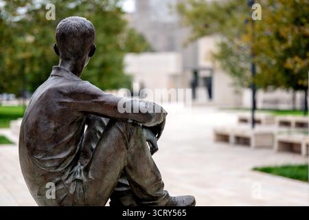 Dwight D Eisenhower Memorial Washington DC // WASHINGTON DC – die Statue der Jungen Eisenhower, eine Bronzeskulptur von Sergej Kazantsev, ist ein zentrales Merkmal des Dwight D. Eisenhower Memorial. Es stellt Eisenhower als jungen Mann aus Kansas dar, der sitzt und auf den Wandteppich des Gedenkwerks blickt und seine Zukunft symbolisiert. Das von Frank Gehry entworfene und im September 2020 geweihte Denkmal ehrt den 34. US-Präsidenten und Obersten alliierten Befehlshaber des Zweiten Weltkriegs. Diese Statue ist eine von drei Bronzeskulpturen von Kasantsev, die sich auf dem Gelände der Gedenkstätte befinden. Stockfoto