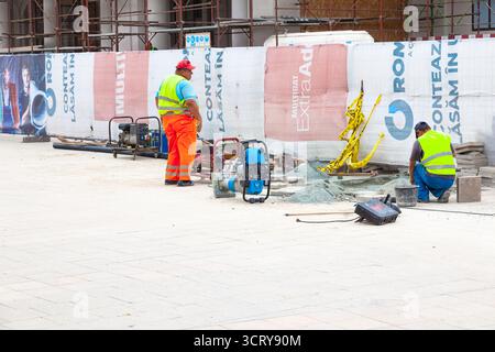 Straßenreparaturarbeiten unter Beteiligung von Personen, Verlegen neuer Pflasterplatten Stockfoto
