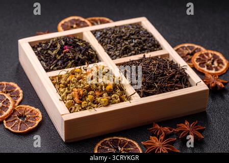 Eine Holzkiste mit verschiedenen Arten von getrocknetem Tee, grünem, schwarzem, Obst und Kamille. Trockener Tee in der Box als Hintergrund für Ihr Design. Stockfoto