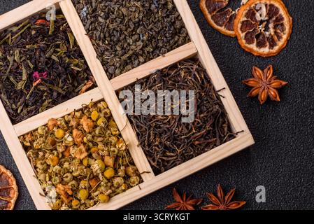Eine Holzkiste mit verschiedenen Arten von getrocknetem Tee, grünem, schwarzem, Obst und Kamille. Trockener Tee in der Box als Hintergrund für Ihr Design. Stockfoto