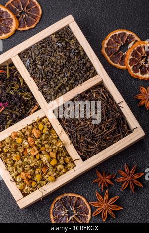 Eine Holzkiste mit verschiedenen Arten von getrocknetem Tee, grünem, schwarzem, Obst und Kamille. Trockener Tee in der Box als Hintergrund für Ihr Design. Stockfoto