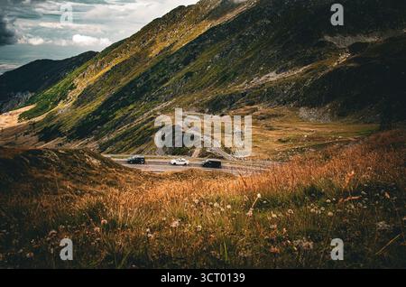 Epischer kurviger Straßenverkehr durch einen zerklüfteten Bergpass unter dramatischem bewölktem Himmel Stockfoto