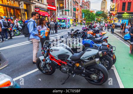 Passanten, die sich eine Reihe von Motorrädern anschauen, darunter Ducati, die am Abend auf der Broadway Street in New York parkten. New York. USA. Stockfoto