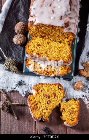 Kürbisrosinenbrot mit Glasur, serviert mit Tee auf dunklem Hintergrund. Halloween-Konzept. Stockfoto