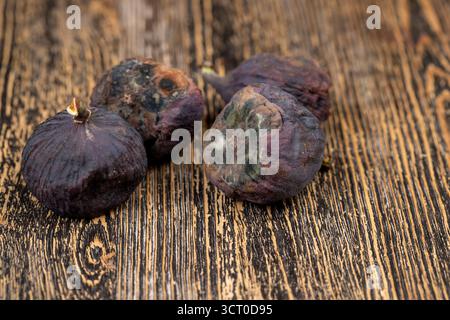 Schimmelige ganze überreife und verdorbene Feigen auf dem Tisch, schimmelige verdorbene Feigen auf dem Holztisch Stockfoto