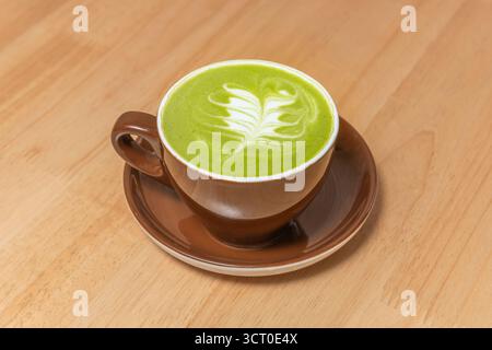 Ein tiefgrünes, geeistes Matcha-Getränk in einem Glasbecher, elegant dekoriert und serviert vor grauem Zementhintergrund Stockfoto