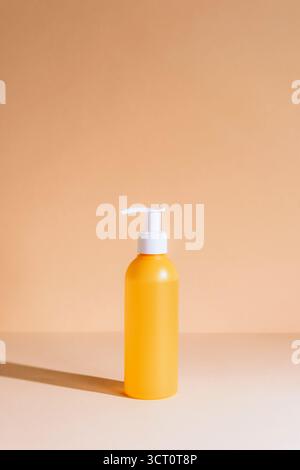 Orangefarbene kosmetische Pumpflasche auf pastellfarbenem Hintergrund. Minimale Zusammensetzung für Hautpflege oder Körperpflege. Nahaufnahme. Stockfoto