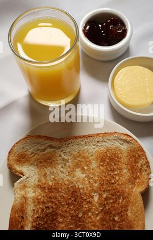 Toast und Orangensaft serviert mit Marmelade und Butter für ein einfaches Frühstück. Cotswolds Country, England Stockfoto