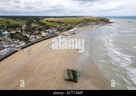 Bei Ebbe spazieren die Menschen am Strand von Arromanches-les-Bains, Normandie, Frankreich, um die Überreste von Mulberry Harbour herum Stockfoto