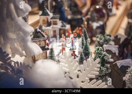 Miniatur-Winterlandschaft mit Figuren, die Schneelandschaft, Eislaufen, Wintersaison und Weihnachtsfeiertage genießen. Stockfoto