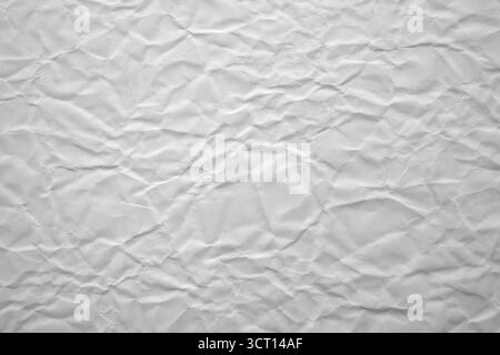 Die Oberfläche des zerknitterten weißen Papiers zeigt eine Vielzahl von Texturen und Mustern, die durch Falten und Falten gebildet werden, und zeigt eine dynamische und haptische Qualität Stockfoto